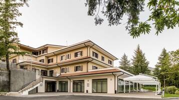 A multi-story hotel with a covered outdoor seating area and a staircase leading to the entrance.