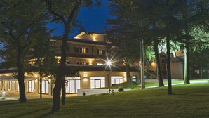 Un edificio de varios pisos con un espacio exterior cubierto, rodeado de árboles.