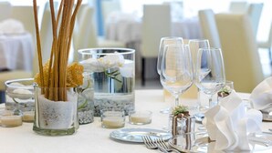 Una mesa de comedor dispuesta con cristalería transparente, un candelabro y un centro de mesa decorativo con ramas y flores.