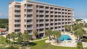 A multi-story hotel with balconies, a swimming pool, and palm trees. - 1BR Fort Morgan Condo | Gulf Views + Pool (GULF SHORES)