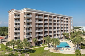 Un hôtel à plusieurs étages doté de balcons, d’une piscine et de palmiers.
