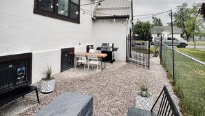 Une terrasse avec des sièges d’extérieur, un barbecue et des guirlandes lumineuses.