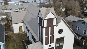 Un bâtiment blanc avec un toit à pignon, une porte en bois et une fenêtre avec des volets.