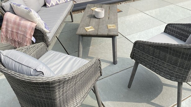 A modern outdoor living space with wicker furniture, a glass door leading to a kitchen, and a view of the backyard. - Spacious Retreat Private Hot Tub Sea/Downs views/patio 10min walk to Beach/Train (seaford)