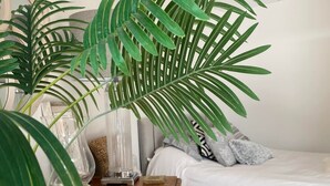 A bedroom with a wooden dresser, a bed with white bedding, and two large green plants. - Spacious Retreat Private Hot Tub Sea/Downs views/patio 10min walk to Beach/Train (seaford)
