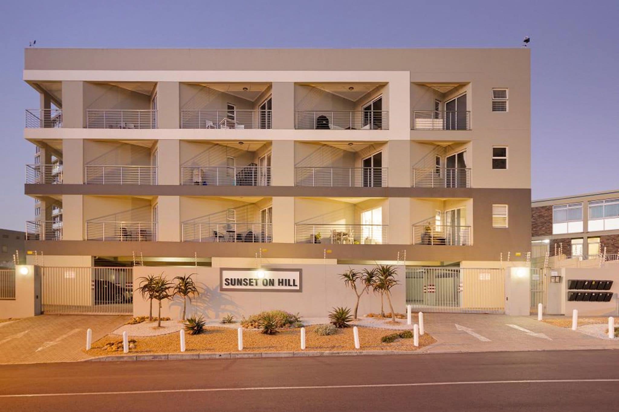A multi-story hotel with a flat facade, balconies, and a sign reading "Sunset on Hill".