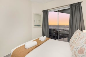 A hotel room with a bed, a view of the sea, and a balcony with a table and chairs. - Sunset On Hill 3 (Cape Town)