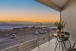 A balcony with a view of a road and ocean at sunset. - Sunset On Hill 3 (Cape Town)