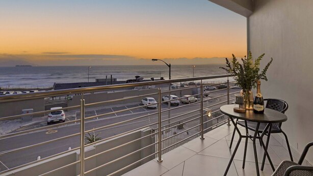 A balcony with a view of a road and ocean at sunset. - Sunset On Hill 3 (Cape Town)