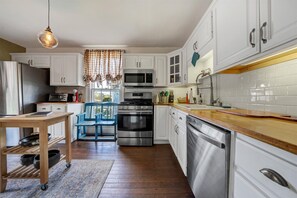 A modern kitchen with white cabinets, stainless steel appliances, and a wooden dining table.