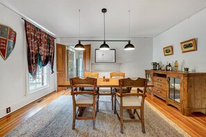 A dining room with a wooden table and chairs, a chandelier, and a cabinet with glass doors.