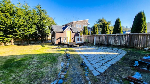 A backyard with a wooden deck, a shed, and a stone pathway.