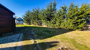 A backyard with a lawn, a wooden deck, and a wooden shed.
