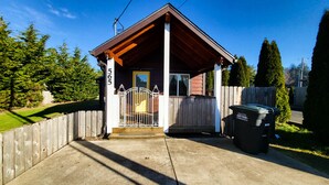 A small, single-story building with a wooden porch and a metal gate. - Bay Street Retreat - Waldport (Waldport)