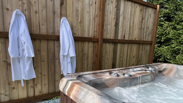 A hot tub with a wooden deck and a patterned mat. - Bay Street Retreat - Waldport (Waldport)