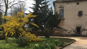 Un chemin pavé mène  à un bâtiment doté d’une façade en pierre et d’une petite fenêtre.