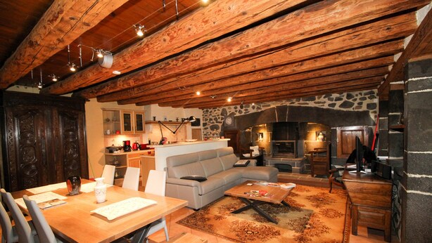 Un salon chaleureux avec un plafond en bois, un mur en pierre et une cheminée.