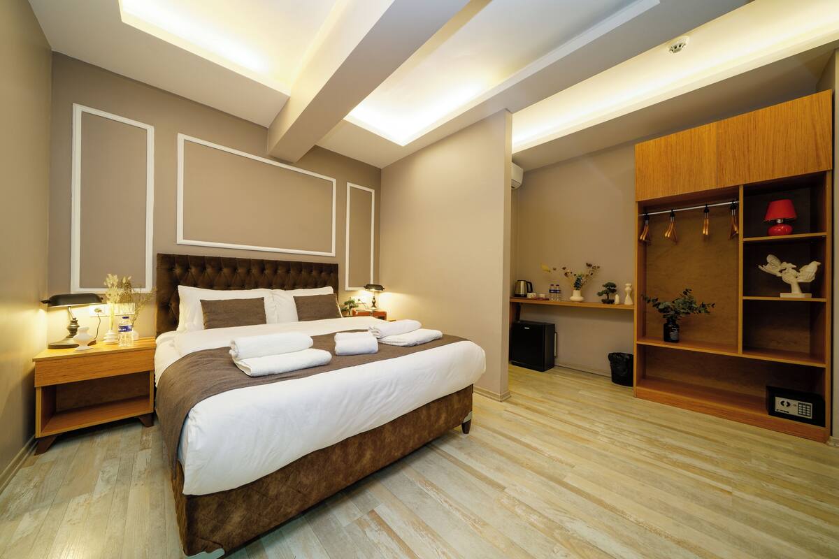 A modern bedroom with a large bed, bedside tables, a wardrobe, and a desk.