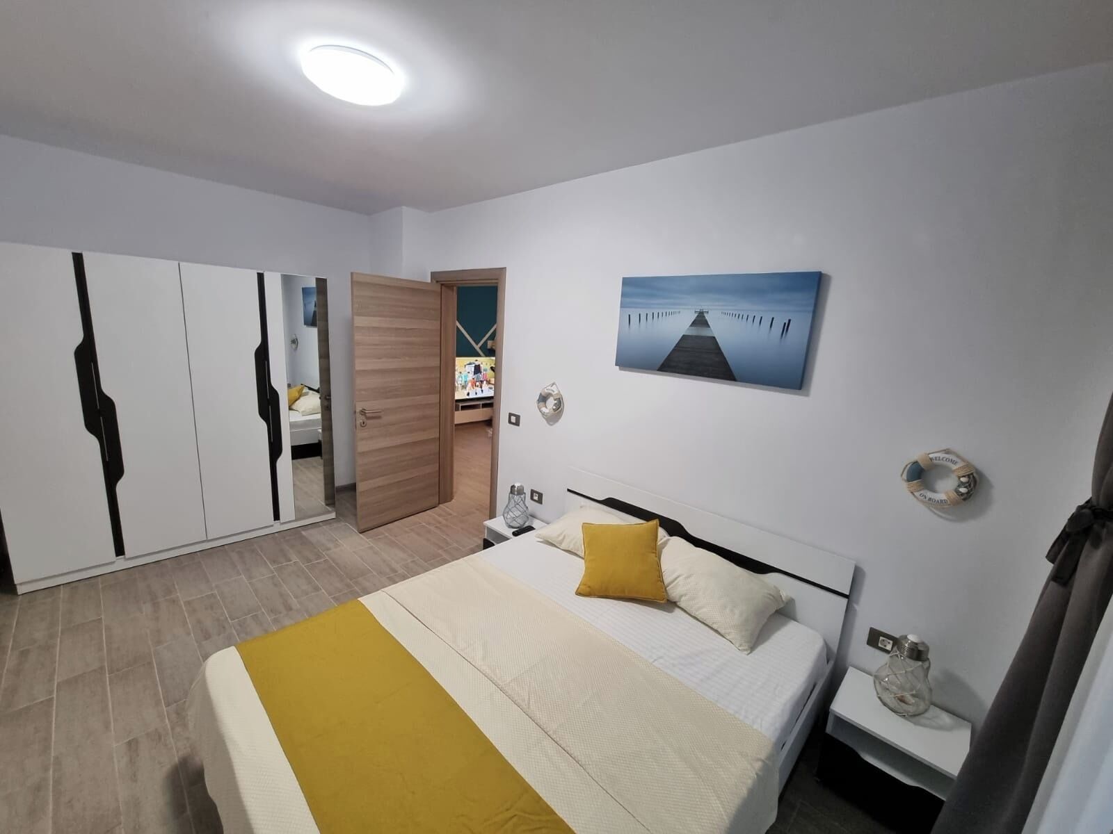 Un dormitorio con cama, armario, un cuadro y una mesita de noche.
