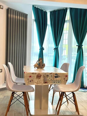 A dining area with a table, chairs, and curtains.