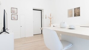 Ett modernt, minimalistiskt rum med ett vitt skrivbord, en stol och en dörr som leder till ett annat rum.