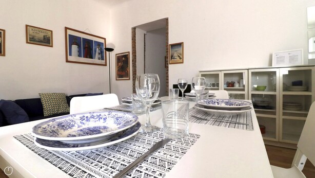 A dining area with a white table set for two, featuring blue and white patterned plates and a black and white table runner. - Italianway Easy - Bligny 64 (Milan)