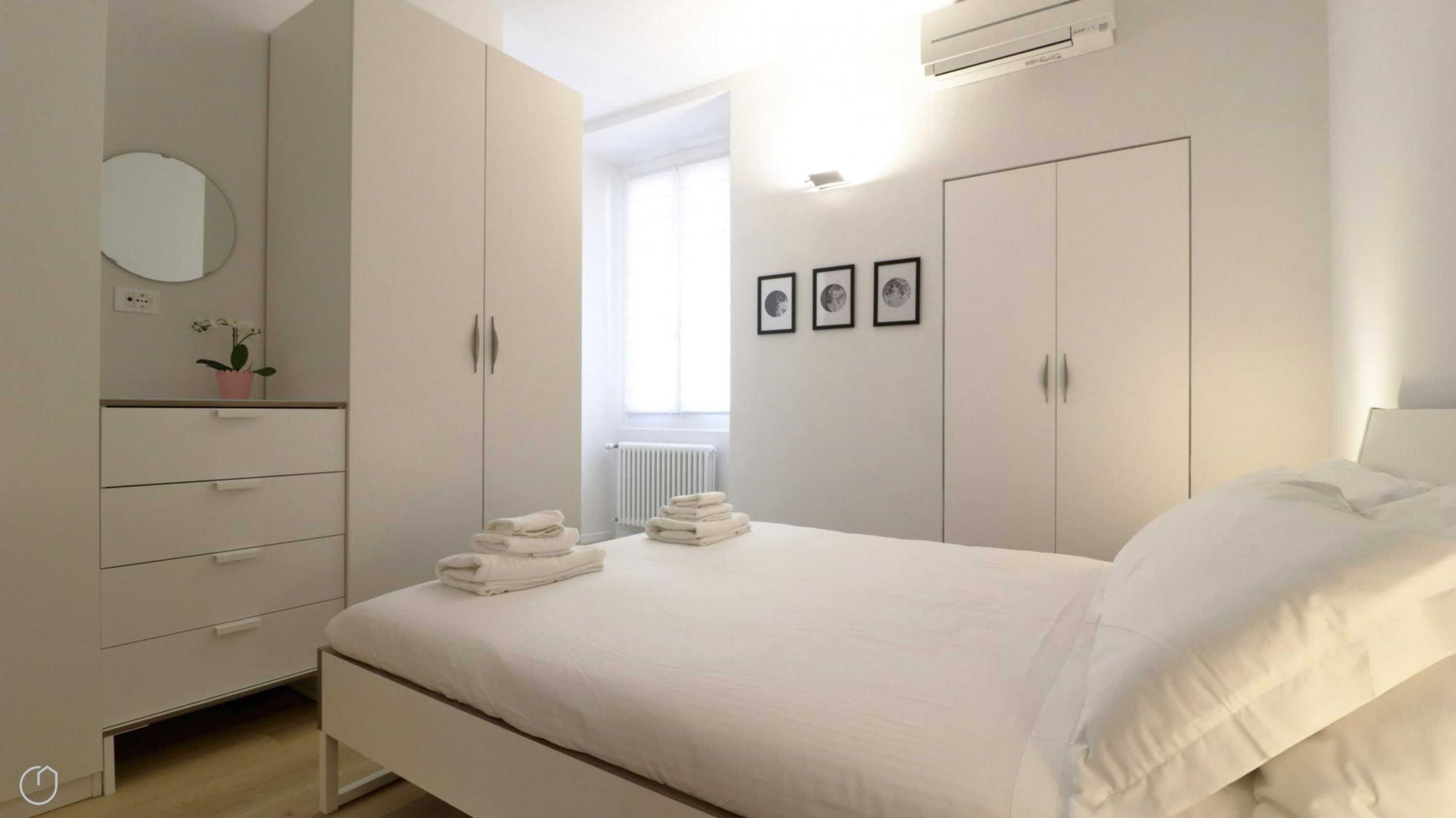 A bedroom with a bed, a wardrobe, a radiator, and a window.