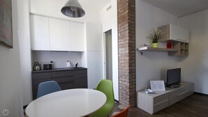 A modern kitchen with white cabinets, a stainless steel kettle, and a hanging light fixture. - Italianway Easy - Ciaia 6 A (Milan)