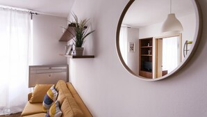 A modern living room with a sofa, a round mirror, a plant on a shelf, and a wooden cabinet. - Cirillo 14 - Apartment Milan (Milan)