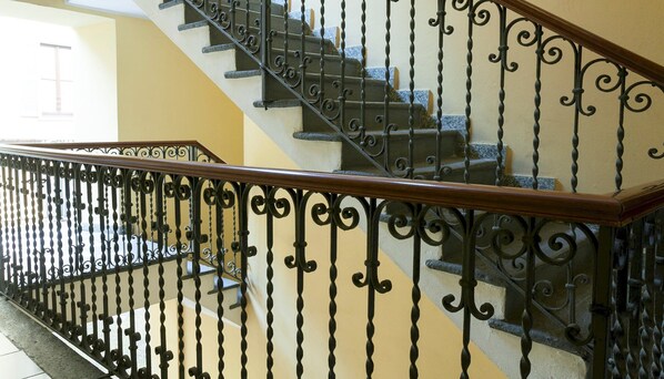 A staircase with ornate black metal railings and a wooden handrail.