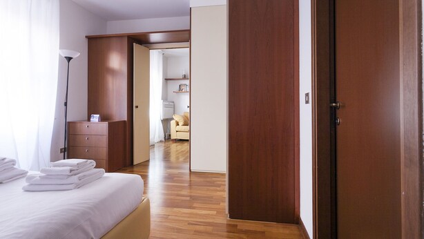 A hotel room with a bed, a wooden wardrobe, a desk, and a chair. - Cirillo 14 - Apartment Milan (Milan)