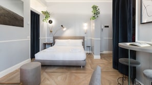 A modern hotel room with a large bed, a round table, and two bedside tables.
