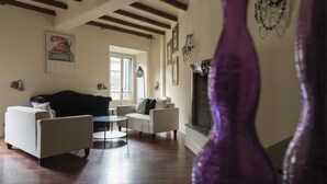 A living room with a black sofa, two white armchairs, a round coffee table, and a fireplace. - Italianway Easy - Argelati 12 Bilo (Milan)