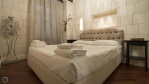 A neatly made bed with folded towels, a bedside table, and a wall-mounted clock. - Italianway Easy - Argelati 12 Bilo (Milan)