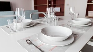 Een eettafel gedekt met witte borden, kommen, glazen en bestek, met een placemat waarop iconen en de tekst 'italianway' staan.