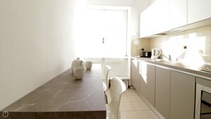 A modern kitchen with a marble countertop, white cabinets, and a view of the outdoors. - Italianway Comfort - Bergognone 47 B (Milan)