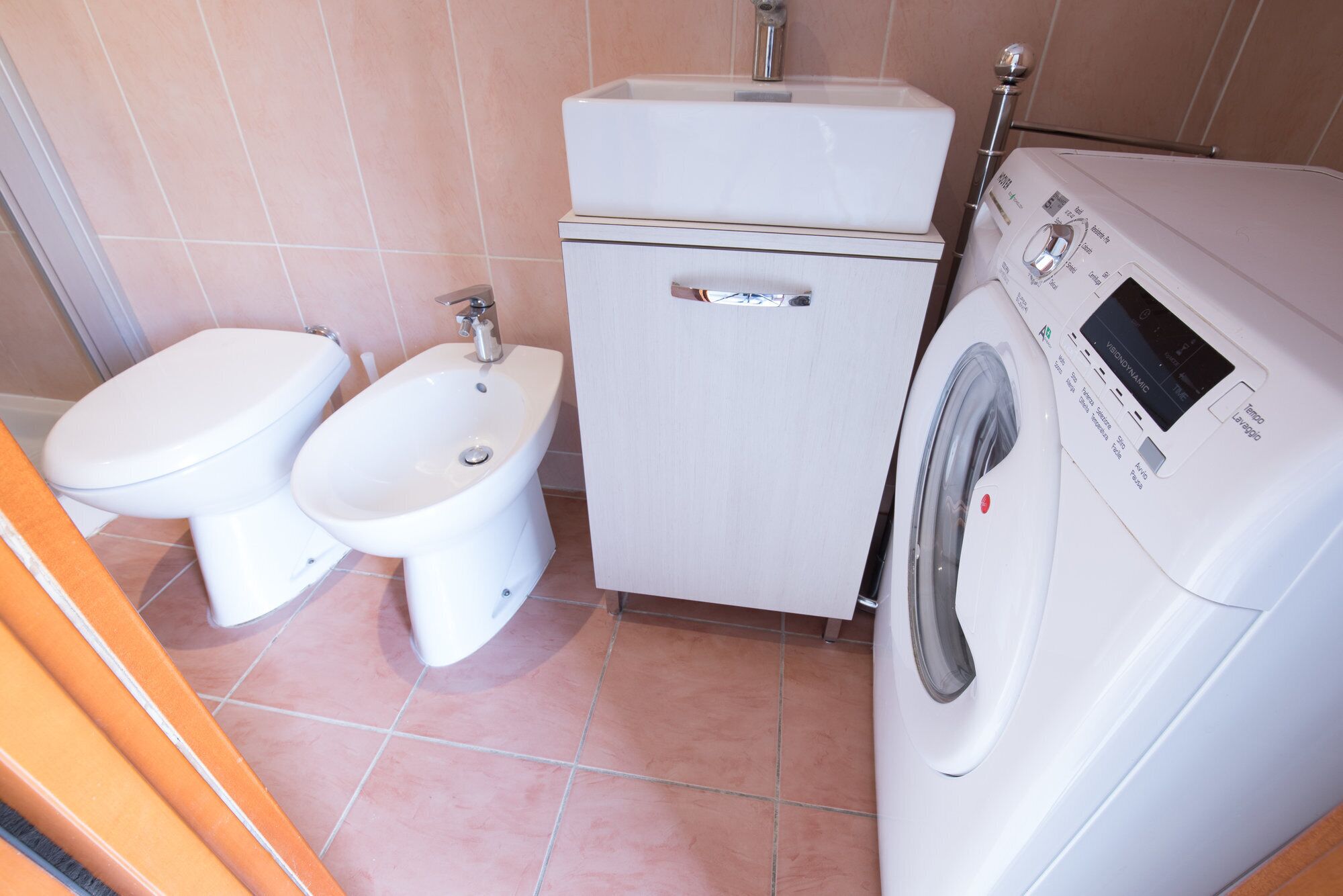 A compact bathroom with a toilet, bidet, and a front-loading washing machine.