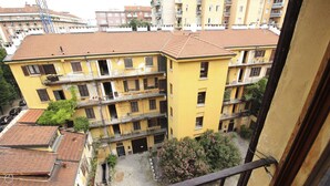 A multi-story yellow building with balconies, a courtyard, and neighboring buildings. - Bligny 39 B (Milan)