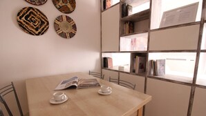 A cozy reading area with a wooden table, two white cups, and a bookshelf filled with books. - Bligny 39 B (Milan)