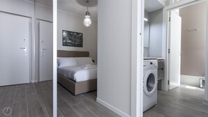 A modern hotel room with a bed, a washing machine, and a bathroom visible through an open door. - Italianway Easy - Cadorna 10 Mono A (Milan)
