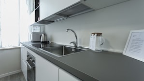 A modern kitchen with a stainless steel sink, a kettle, and a clear glass mug on the counter. - Italianway Easy - Cadorna 10 Mono B (Milan)