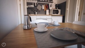 Une table à manger avec une machine à café, une tasse et une assiette, le tout préparé pour deux personnes.