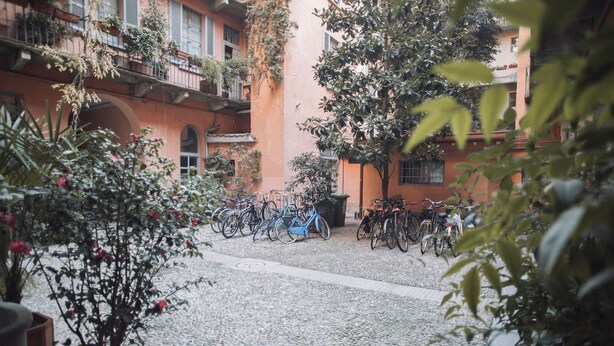 Une cour intérieure où sont garés des vélos, entourée d’immeubles dotés de balcons et de plantes en pot.