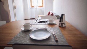 Une table à manger avec un set de table, une tasse, une assiette, des couverts et une cafetière.