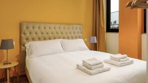 A neatly made bed with white linens and two folded towels on the bed. - Mono A (Milan)