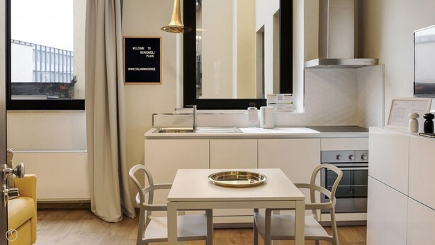 A modern kitchen with a dining area, a stainless steel sink, and a table with a tray. - Mono A (Milan)