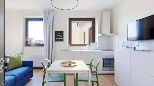 A compact kitchen with a dining table, chairs, a TV, and a view of the city through a window. - Mono A (Milan)