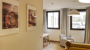 A living room with a sofa, a dining table with chairs, and large windows with curtains. - Mono B (Milan)
