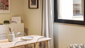 A dining area with a wooden table, clear chairs, a white vase with chopsticks, and a framed picture on the wall. - Mono B (Milan)