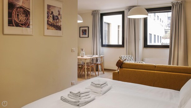 A hotel room with a bed, a sofa, a dining table with chairs, and artwork on the walls. - Mono B (Milan)